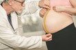 © thodonal - Doctor measuring belly size of pregnant woman