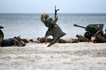 Soldiers fighting on the beach during the reconstruction of the historical battle with WWII