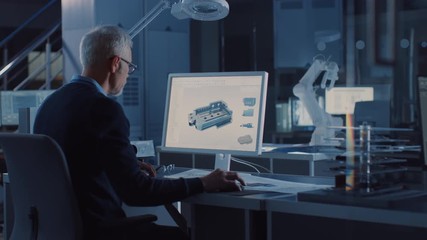 Leinwandbilder - Engineer Works on Computer Uses CAD Software to Design 3D Industrial Machinery Component. In the Background Robot Arm Concept Standing in Heavy Industry Engineering Facility. Over the Shoulder Shot