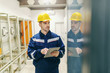 © dusanpetkovic1 - Electrician in uniform and helmet on head using tablet and checking on dashboard in control room in heavy industry plant.