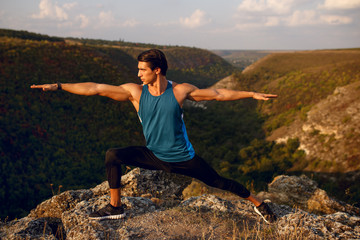 Wall Mural - Athlete, muscular, fit, abs, young man doing stretching exercises before workout outside on forest, mountain background. Summer landscape. Copy space.