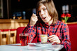 © Iryna - Portrait of teenager boy drinking tea with dessert having breakfast in cafe.