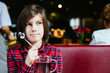 © Iryna - Close up portrait of teenager boy drinking tea sitting on red couch having breakfast in cafe interior.