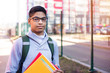 © Oleksandr - Portrait of African American student in glasses with books. Black young man smiling is standing on the street holding textbooks in his hands.