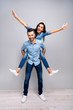 Full length vertical body size photo funky cheer she her he him his lady guy piggyback ride walk meet adventures hands arms spread up wear casual jeans denim shirts clothes isolated grey background