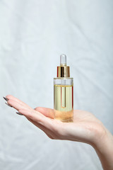 Pipette bottle with cosmetic oil in female hand. Skin care product