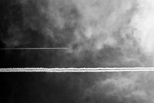 Two Planes In Dark Sky With White Clouds. The Aircraft Leaves Traces. Black And White