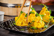 Pan-Asian cuisine concept. Wontons of yellow dough, minced meat. Japanese dumplings with minced meat. Serving dishes in the restaurant on a black plate. Background image copy space