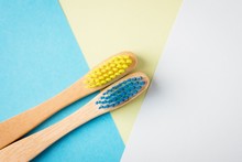 Yellow And Blue Bamboo Toothbrushes. Eco-friendly Concept. Minimal, Geometric Background. Top View, Copy Space