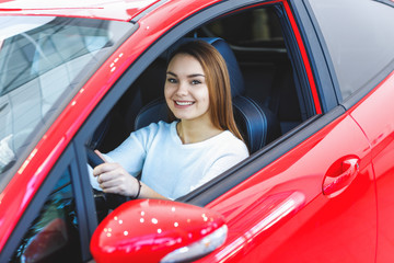 Beautiful happy woman choosing a car at the dealership