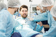 © Nestor - Group of surgeons holding scared male patient on surgery table