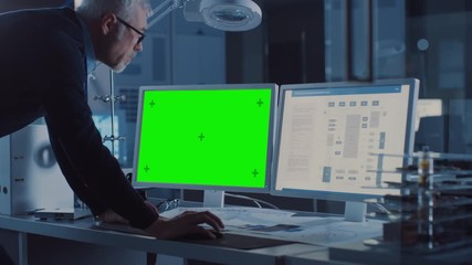 Leinwandbilder - Professional Engineer Works on Computer with Green Mock-up Screen and Integrated Development Programming on Display. In the Background Industrial Electronics Design Agency. Over the Shoulder Shot
