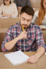 Handsome young man studying in university auditorium