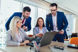 © Mediteraneo - Group of young business people working and using laptop while sitting at the office desk together. Selective focus.