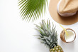 Summer mood concept. Tropical background with ripe organic pinapple with leafy crown, cracked coconut with milk and straw, broad brim hat. Flat lay, top view, copy space, isolated.