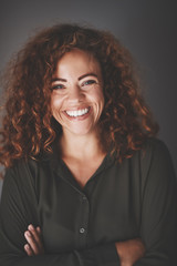 Laughing businesswoman standing against a gray background