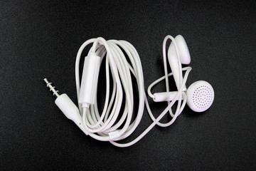 Earphone or earphones on black background.the white earphones for using digital music or smart phone | earbuds isolated. Top view