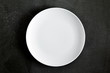 © prime1001 - Empty white plate on black background table. Flat lay, top view, copy space