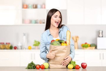 Wall Mural - Beautiful woman standing on the kitchen with grocery shopping bag