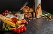 © MONIUK ANDRII - Mix cheese on dark background on wood board with grapes, honey, wine, bread, nuts, tomatoes and basil. Top view.