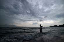 Silhouette Of Girl Standing In Sea Against Cloudy Sky