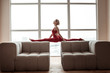 Elastic skinny girl doing yoga on furniture in living room