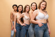 © LIGHTFIELD STUDIOS - five pretty multicultural girls in blue jeans and bras smiling and looking at camera isolated on beige, body positivity concept