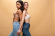 © LIGHTFIELD STUDIOS - two pensive multicultural girls holding hands while standing back to back isolated on beige