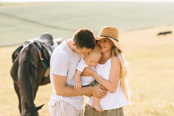 A young family have a fun in the field. Parents and child with a horse