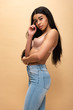 © LIGHTFIELD STUDIOS - beautiful african american girl in blue jeans and bra looking at camera isolated on beige