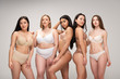Five smiling multiethnic girls smiling and posing at camera isolated on grey, body positivity concept