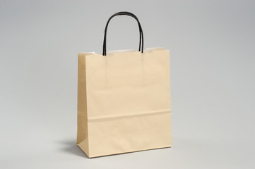 Yellow craft paper bag with shopping handles in the studio