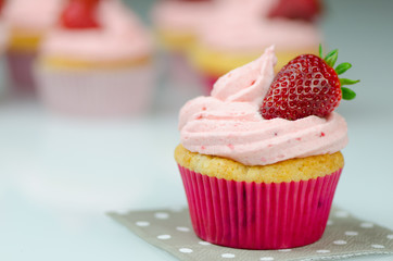 Delicious pink strawberry cupcake with a strawberry. Cupcakes and pink icing with a strawberries on top