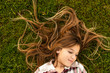 © Westend61 - Smiling girl with long hair lying on a meadow