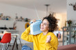 © Westend61 - Carefree woman listening to music with portable radio at home