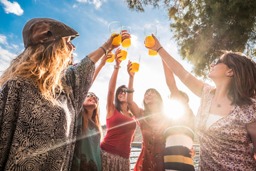 Group of friends young beautiful caucasian women have fun and celenbrate all together toasting with healthy orange juice and smile for friendship and relationship concept