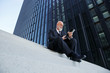 © Westend61 - Elegant businessman, sitting on stairs in the city, using digital tablet