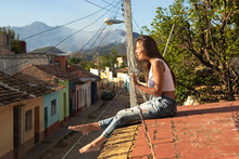 Young Woman Is Sitting On The Roof Of Old House