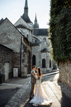 Attractive Modernt Newlyweds Hugging And Kissing On The Street Of The Old Town. Wedding Day