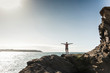 © Westend61 - Young woman hiking on a rocky beach, looking at view