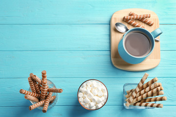 Wall Mural - Chocolate wafer rolls, marshmallows and cup of cocoa on wooden background, top view with space for text