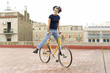 © Westend61 - Portrait of happy young woman balancing on bicycle in the city