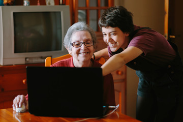 Wall Mural - Granddaughter teaching her grandmother how to use a computer