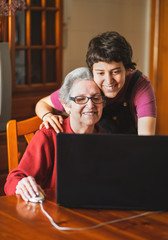 Wall Mural - Granddaughter teaching her grandmother how to use a computer