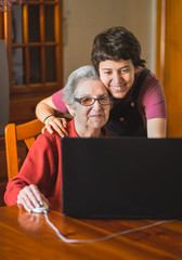 Wall Mural - Granddaughter teaching her grandmother how to use a computer