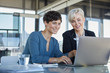 © Westend61 - Two smiling businesswomen sharing laptop at desk in office