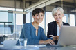 © Westend61 - Portrait of two smiling businesswomen with laptop at desk in office