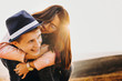 © Strelciuc - Beautiful adult couple having fun while girl is piggybacking his boyfriend against sunset while traveling.