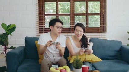 Wall Mural - Two of young Asian couple family relaxing on sofa playing game, Asian lifestyle at home concept