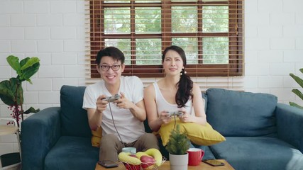 Wall Mural - Two of young Asian couple family relaxing on sofa playing game, Asian lifestyle at home concept